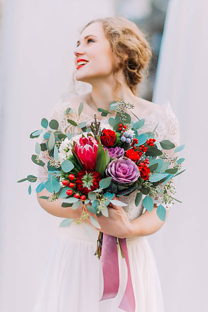 istock Gorgeous blond bride holding her vintage wedding bouquet with red 514624446