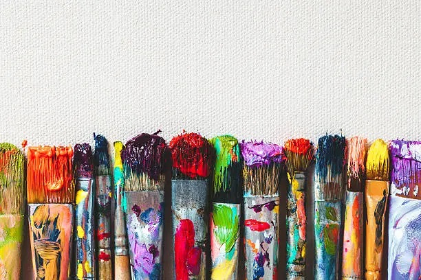Photo of Row of artist paintbrushes closeup on canvas.