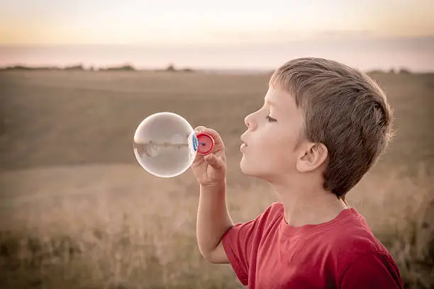 Photo of Boy blowing up the soap bubbles