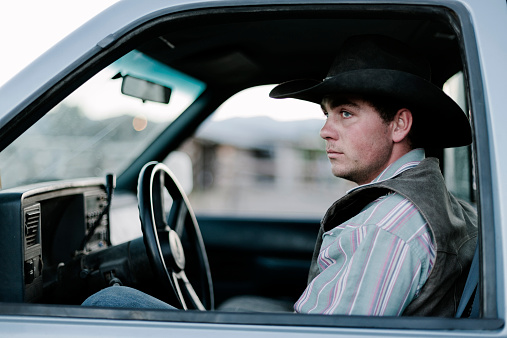 A cowboy sits in his pick-up truck, Parade Rest Ranch, Montana, USA. 