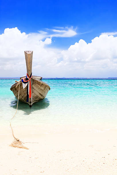 Long tail wooden boat stranded at Krabi island beach in Thailand.