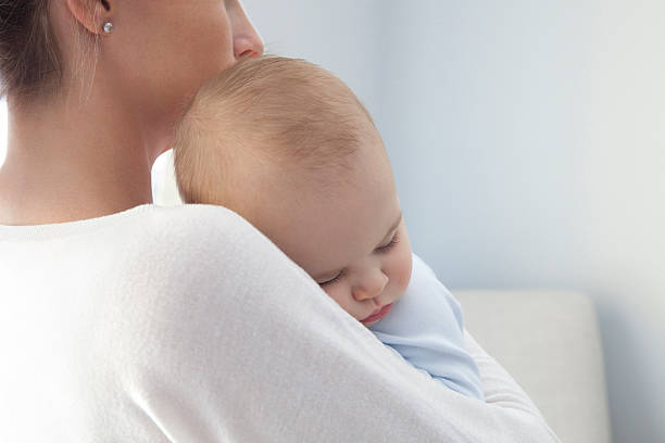 Baby Boy Sleeping On His mother's Arms stock photo