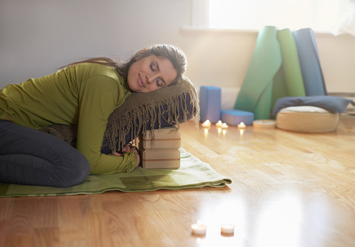 Serene lady relaxing and meditating on a yoga mat in a cosy house