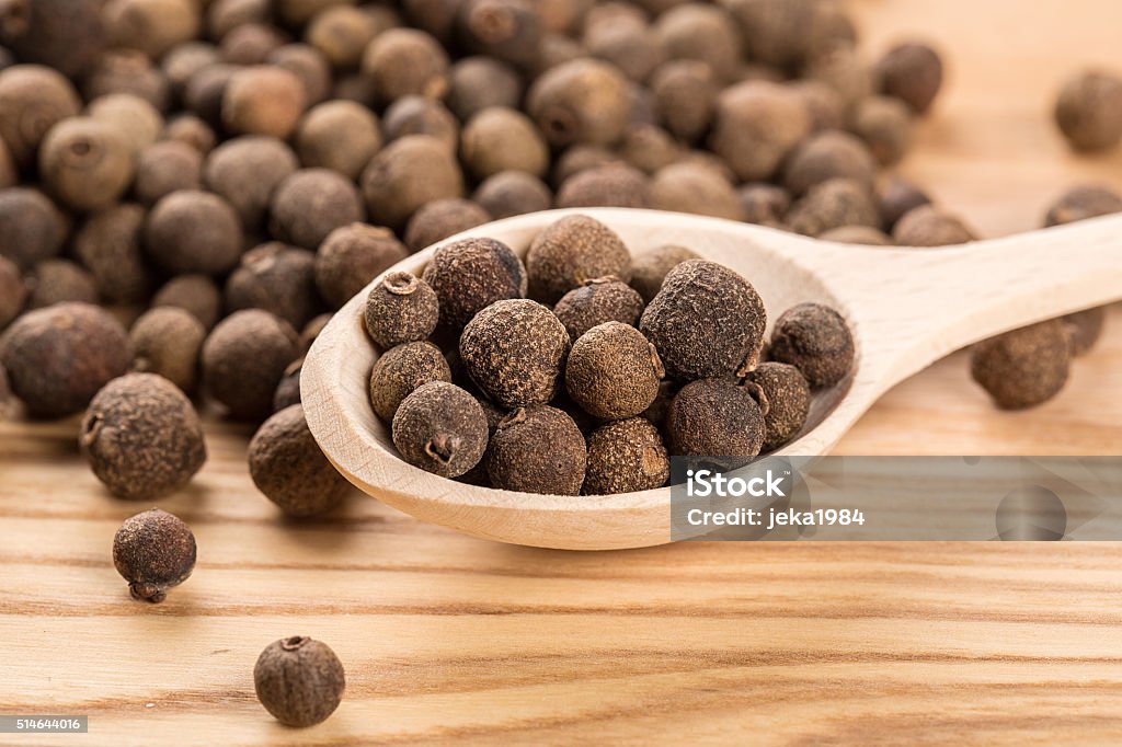 allspice in a wooden spoon on the wood table Allspice Stock Photo