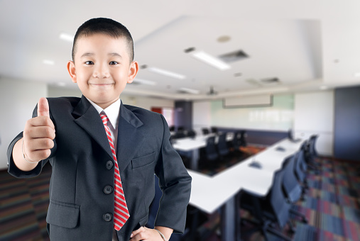 Happy smile little business boy in conference hall background
