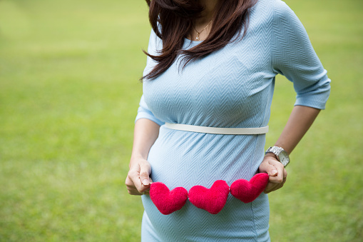 Asia mujer embarazada en vestido azul sosteniendo corazón forma Accessori photo