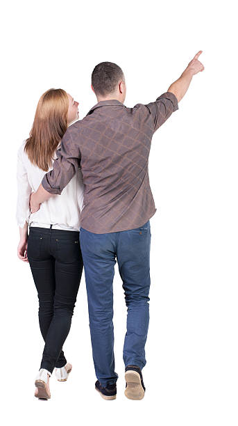 istock Back view of walking young couple (man and woman) pointing. 514651315