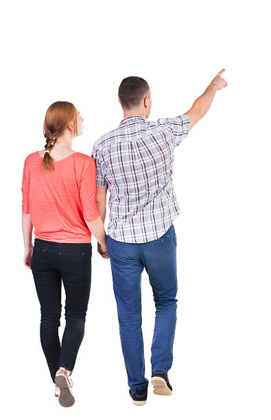 istock Back view of walking young couple (man and woman) pointing. 514653683