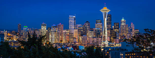 Seattle Space Needle downtown skyscrapers illuminated at dusk Washington panorama Panoramic view across skyline of Seattle, the iconic spire of the Space Needle and the crowded skyscrapers of downtown brightly illuminated against the blue dusk sky, Washington, USA. ProPhoto RGB profile for maximum color fidelity and gamut. elliott bay photos stock pictures, royalty-free photos & images