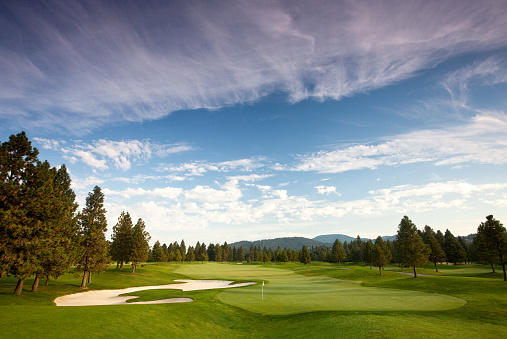 A beautiful golf course in the mountains. Idaho, United States. Golf resort in the pacific northwest. Beautiful landscaping and turf grass maintenance on this course. Dramatic summer sky with bentgrass greens and fairways. Nobody in the image. Golf course scenic. 