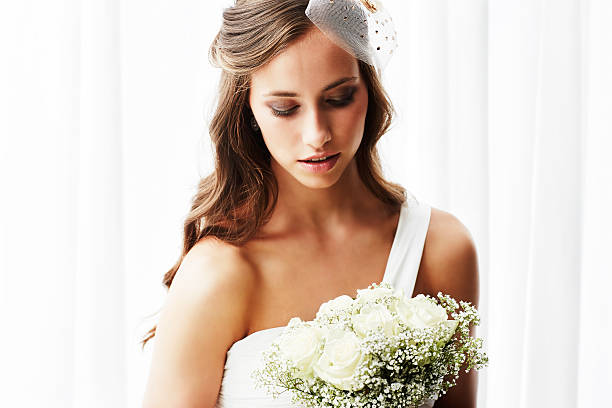 istock Young bride in wedding dress holding bouquet, studio shot 514654603