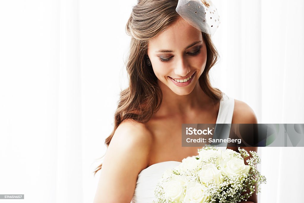 Young bride in wedding dress holding bouquet, studio shot Bride Stock Photo