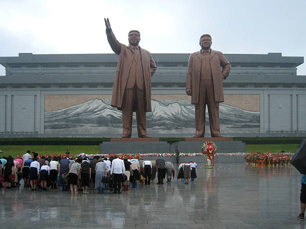 Grand Monument in Pyongyang, North Karea Pyongyang, North Korea - August 15 2012: North Koreans showing their respect to their political leaders at the Grand Monument on Mansu Hill with the bronze statues of Kim II Sung and Kim Jong II. cold war photos stock pictures, royalty-free photos & images