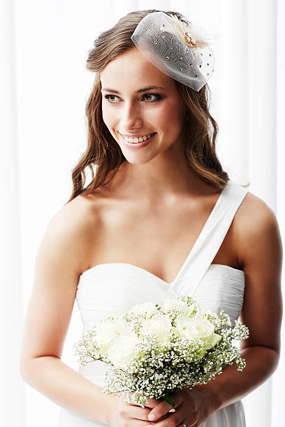 istock Young bride in wedding dress holding bouquet, studio shot 514658683