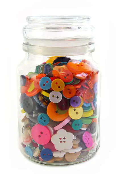 Colorful Haberdashery buttons in a glass jar. Vertical on White background.