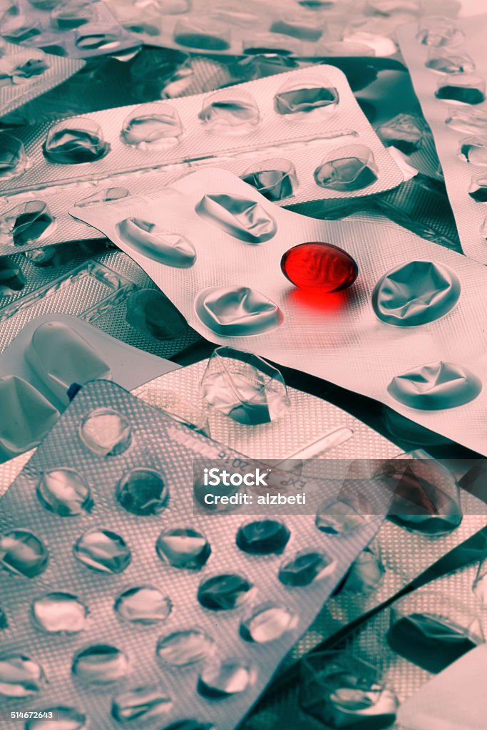 Red oil pill One red transparent oil pill on foil packaging Addiction Stock Photo