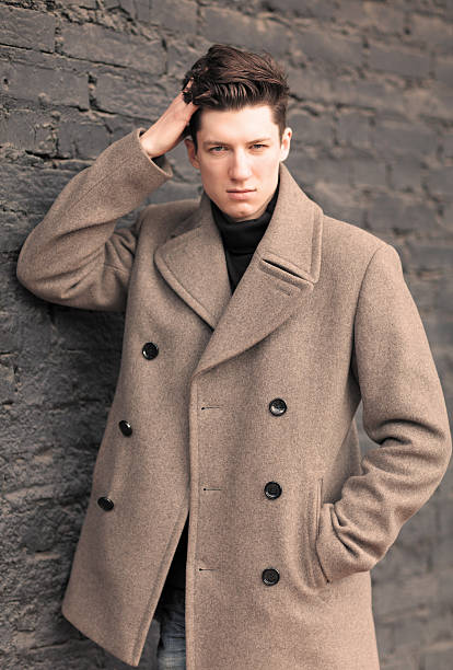 istock Man Model in a coat Poses at a brick wall. 514675765