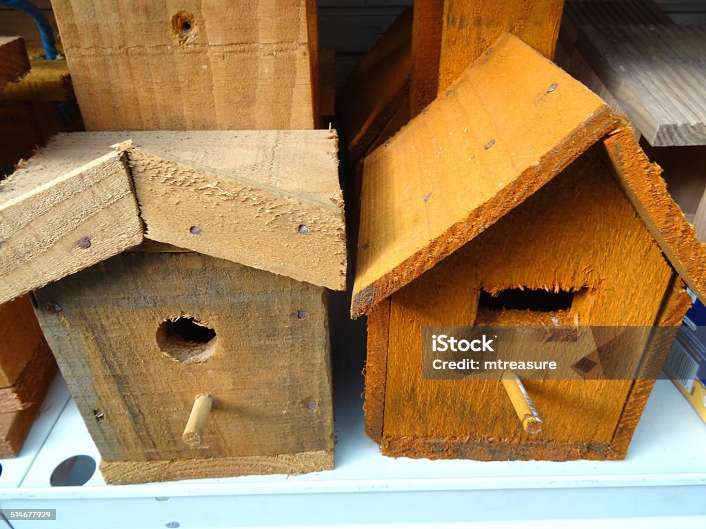 Image of wooden nest boxes, birdboxes, bird nesting boxes, perches Photo showing two different wooden nest boxes / birdboxes, with peaked triangular tops and a perch next to the entrance hole (round and rectangular / square entrance holes).  Many bird and wildlife enthusiasts recommend not having a perch by the hole, to prevent other birds perching outside and pestering the nesting birds inside. Bird's Nest Stock Photo