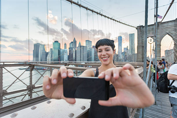 istock Pretty Young Woman Taking Selfie on Brooklyn Bridge 514686509