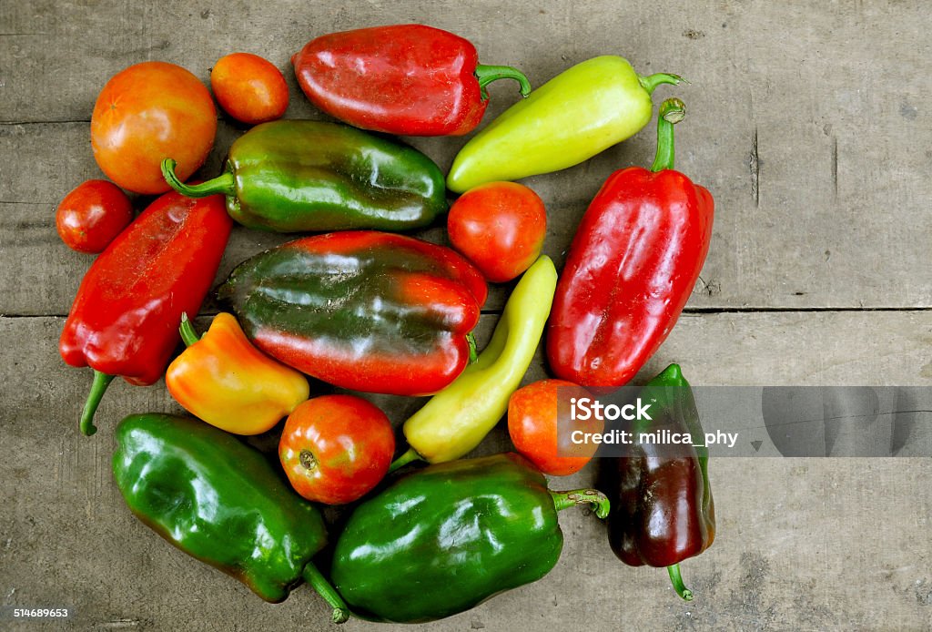 Red and green peppers and tomato red and green peppers and tomato on a wooden table Food and Drink Stock Photo