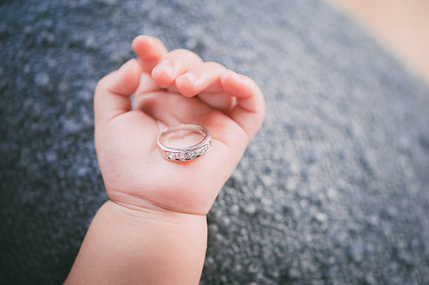 Bebê na mão Pegue um anel de casamento - fotografia de stock