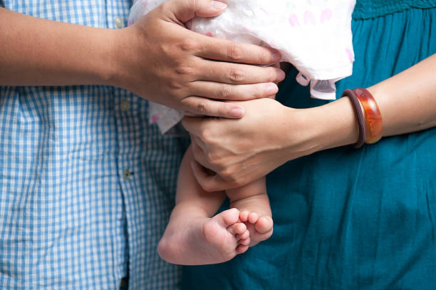 Pés de bebê recém-nascido nas mãos dos pais - fotografia de stock