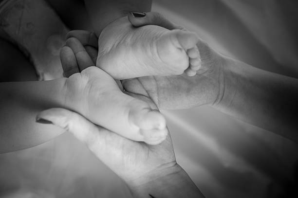 Pés da criança em mãos da mãe - fotografia de stock