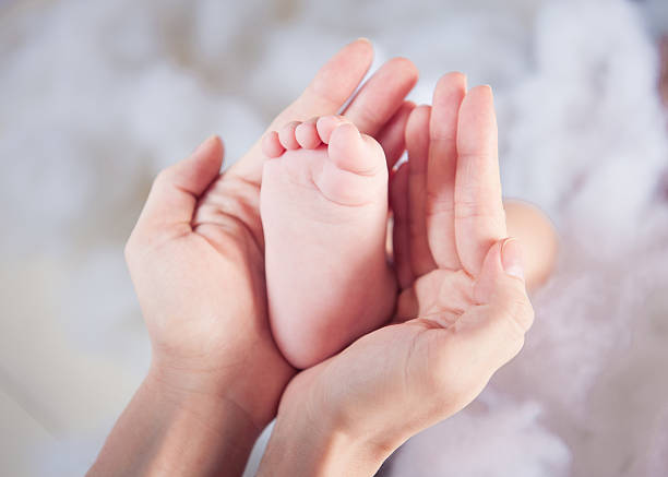 Pequeno bebê pé nas mãos da mãe - fotografia de stock