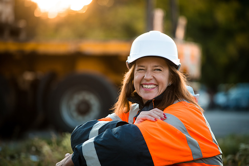 Senior woman engineer wearing protective wear in work - outdoor at sunset