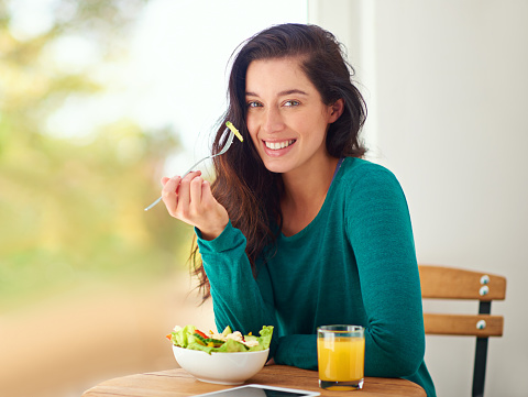 Portrait of a young woman eating a healthy salad at home