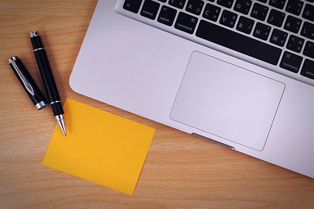 istock Laptop, yellow paper note and pen on wood table. 514715484