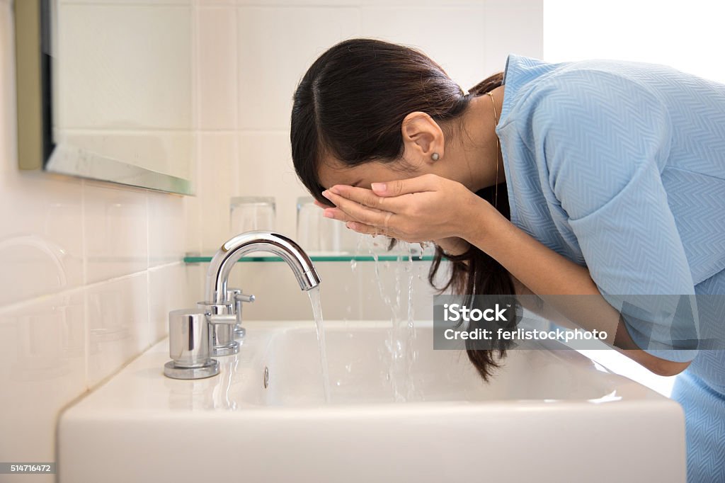 Asian woman washing her face on the sink A portrait of an Asian woman washing her face on the sink Adult Stock Photo