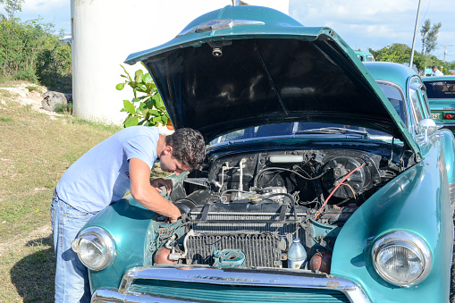 Santiago de Cuba, Cuba - 14 january 2016: man repiring his vintage car at Santiago de Cuba, Cuba