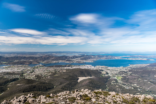 Taken from atop Mount Wellington, Hobart, Tasmania. A panoramic view of Hobart City and surrounding areas with the Tasman Bridge Spanning over the Derwent River that Leads into the Derwent Estuary. Igneous rocks of Mount Wellington are apparent in the foreground. The amospheric conditions from the top of the mountain gives the scene a slight blue haze. The weather is fine with wispy clouds. Taken in the afternoon October 2015 with Nikon D800 - f/4.5 - 1/500 sec. - ISO 200 - 724mm.