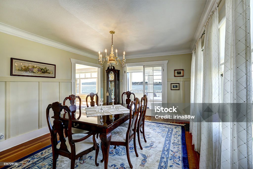 Elegant carved wood dining table set Bright dining room with rich carved wood dining table set and antique grandfather clock Apartment Stock Photo