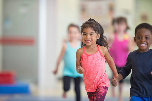 bambini correre in palestra - child playing running group of people foto e immagini stock