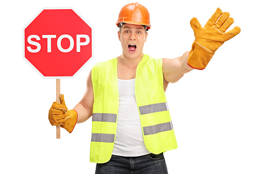 Construction worker holding a stop sign and gesturing with his hand isolated on white background
