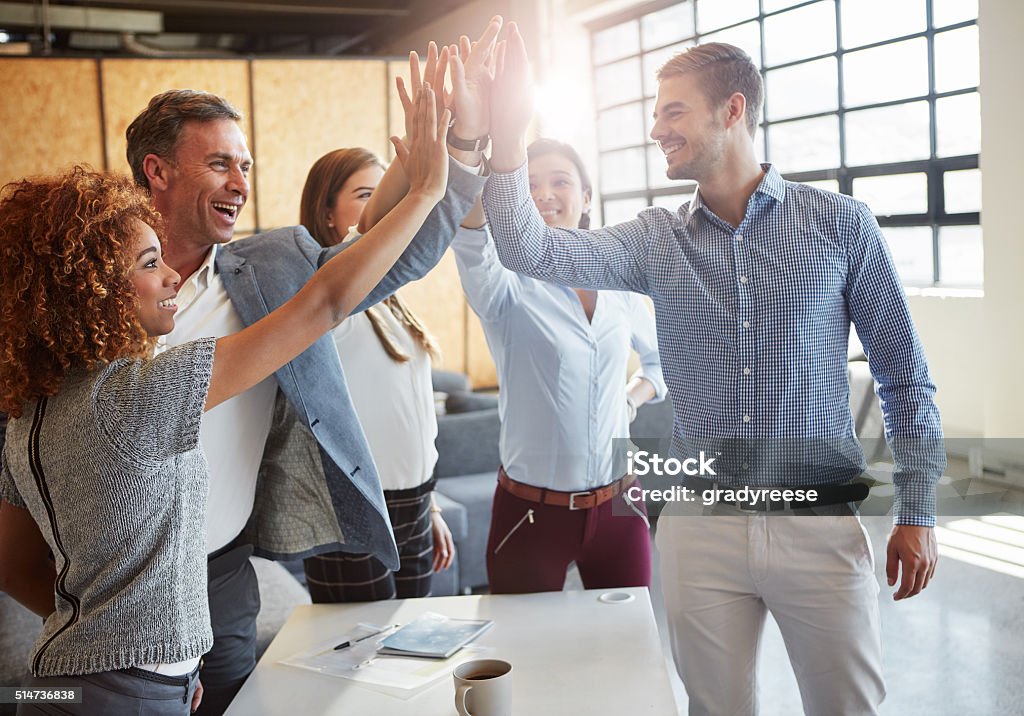 High five! Cropped shot of a group of businesspeople high fiving in the office Cheering Stock Photo