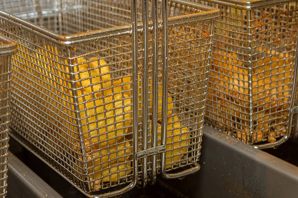 Nuggets are fried in a basket in oil a professional fryer.