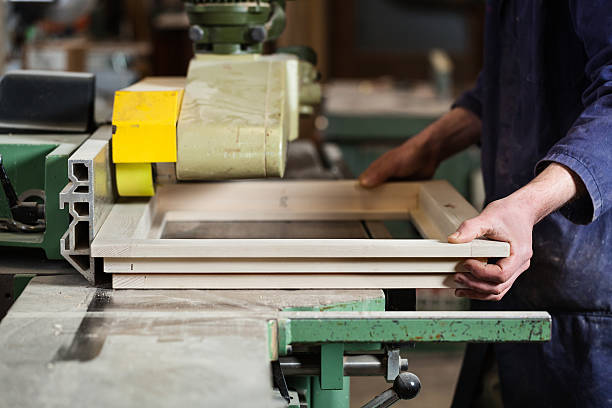 Carpenter's hands cutting wooden window frame stock photo