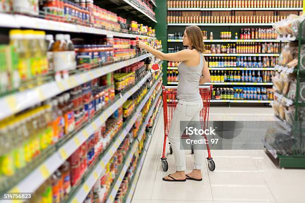Woman Chooses Sauce In The Supermarket Stock Photo - Download Image Now - Savory Sauce, Supermarket, Aisle