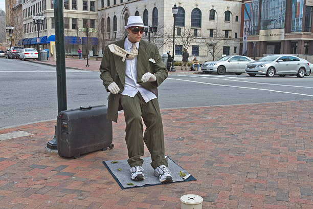 Asheville, North Carolina, USA - March 2, 2014: Living statue performance street artist showing a man in a suit being blown backward and leaning at an impossible angle remains completely immobile on March 2, 2014 in downtown Asheville, NC