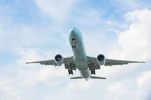 Boeing 777 flying Boeing 777 flying in partly cloudy sky gliding photos stock pictures, royalty-free photos & images
