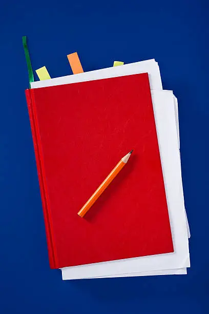 Red diary with pencil on blue background