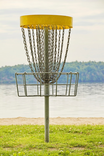 A generic disk golf basket near the water on a lakeside course.