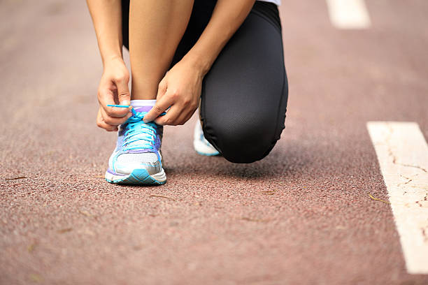 istock woman runner tying shoelaces on trail 514776141