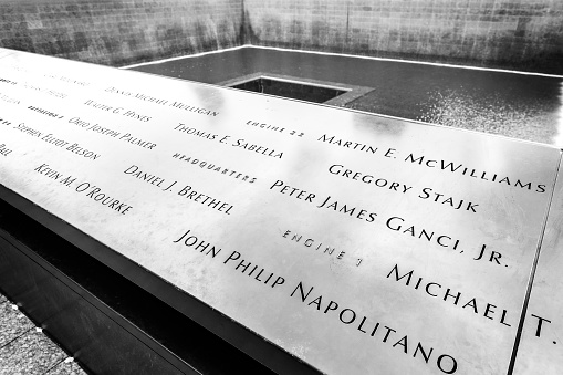 New York, USA - August 16, 2015: Names of the victims of attacks inscribed on the parapets surrounding the waterfalls of National September 11 Memorial.