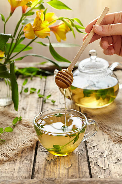 istock Peppermint tea with honey in glass cup, teapot and flowers 514779728