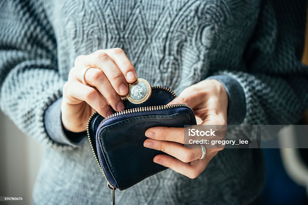 Currency Hands holding british pound coin and small money pouch Poverty Stock Photo