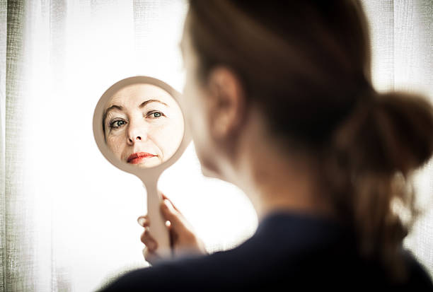 Mirror reflection of mature woman stock photo